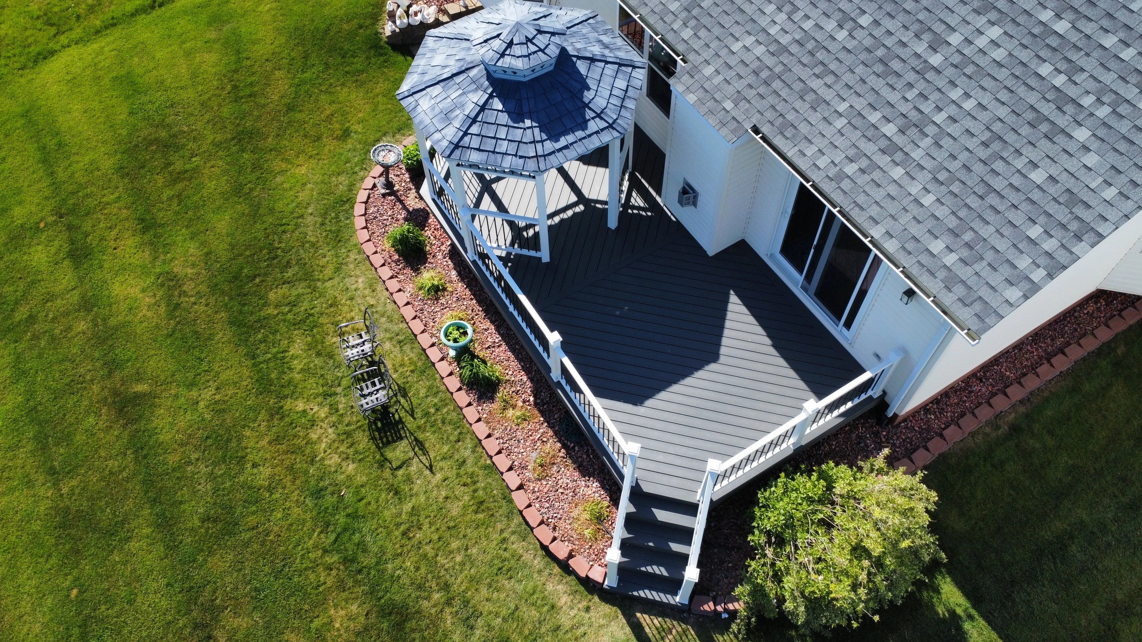 Aerial view of composite deck with gazebo, white railings, and stone landscaping