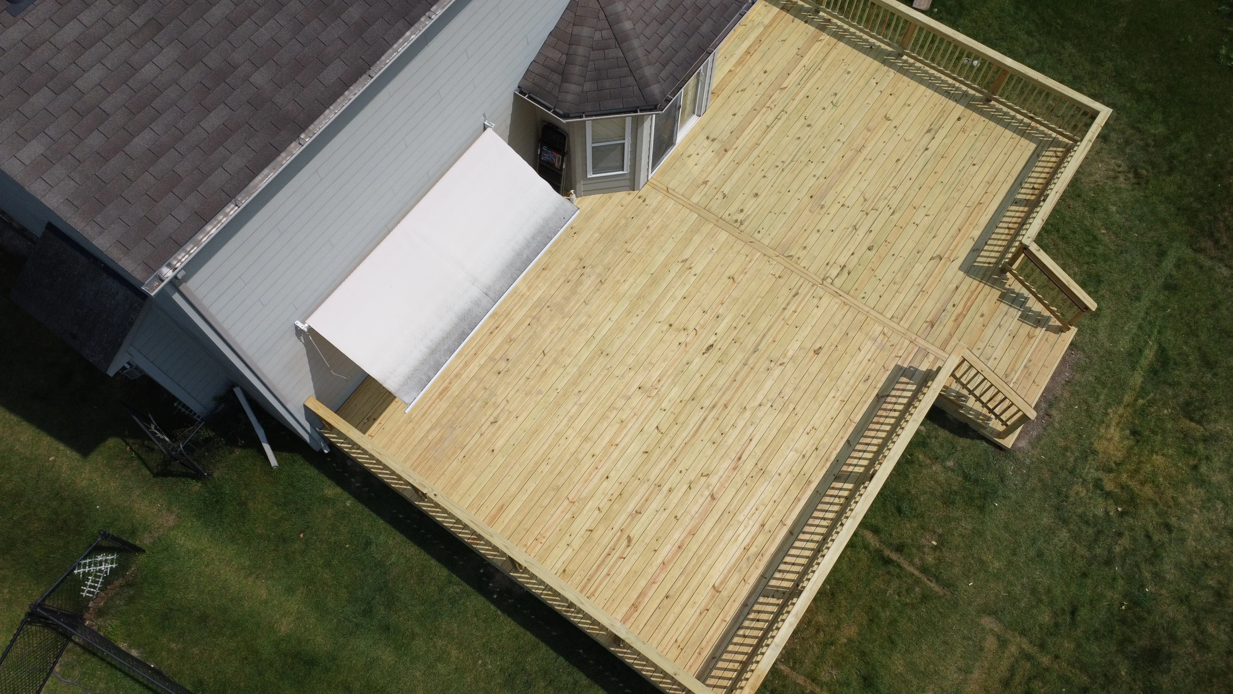 Aerial view of two-level pressure-treated wood deck with stairs and railings attached to home